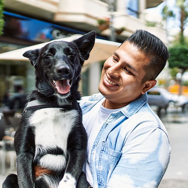 Man Holding Dog Smiling In City